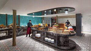 Disposição moderna de buffet com um chef preparando alimentos, diversos pratos e piso de azulejos.