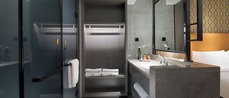 A modern bathroom with a glass shower enclosure, a built-in vanity, and a large mirror.
