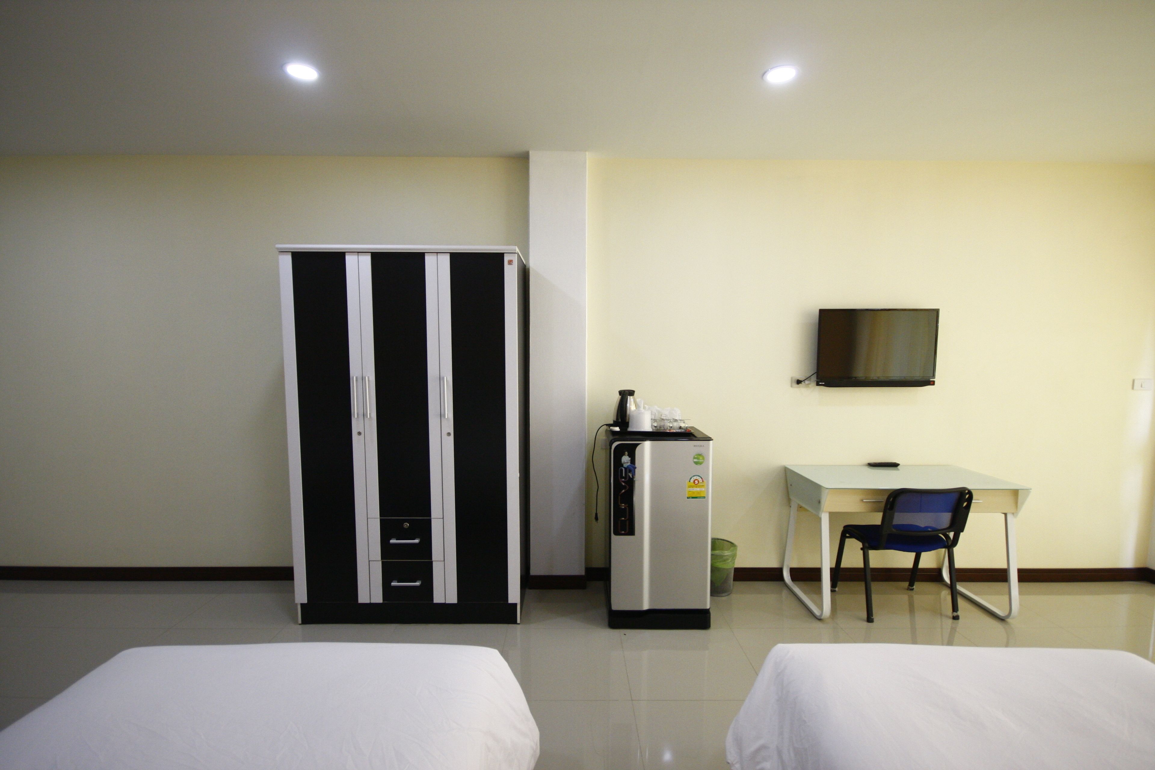 A hotel room with two beds, a desk, a chair, a TV, and a minibar.