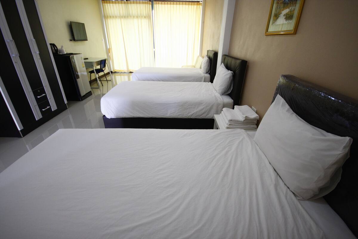 A hotel room with two beds, a desk, and a television on the wall.
