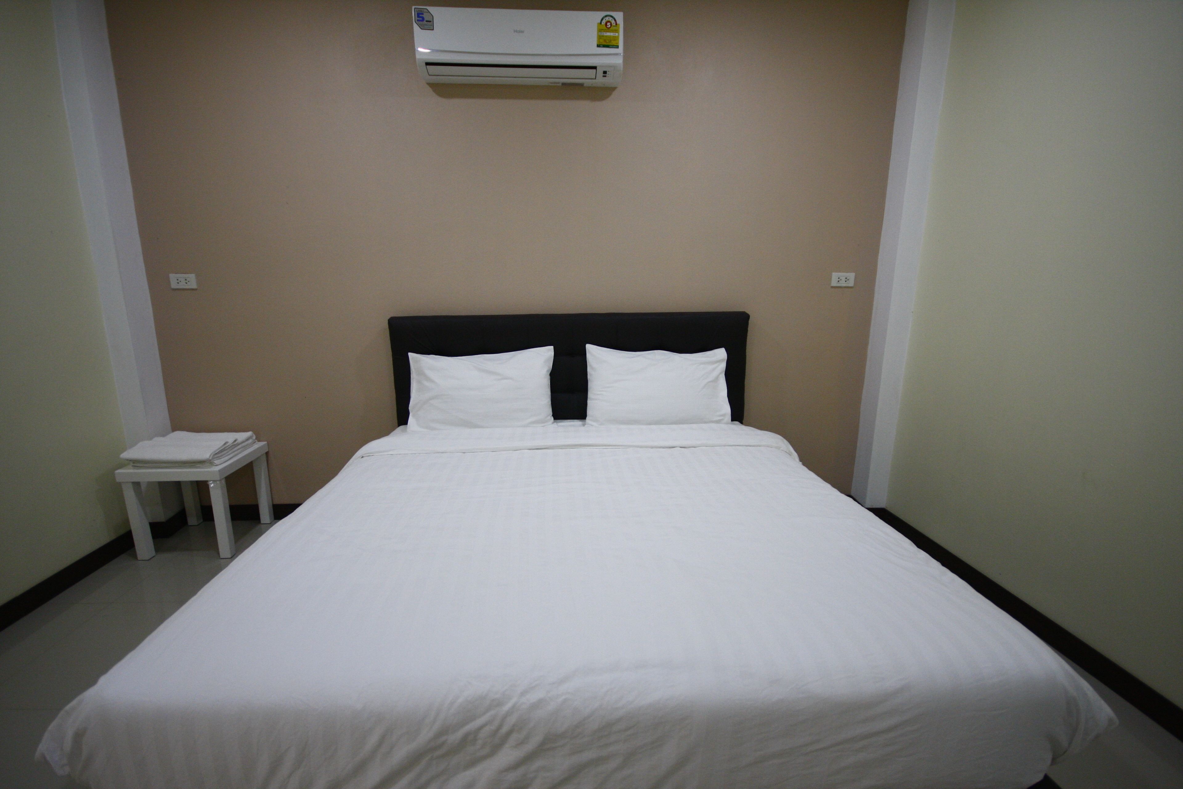 A neatly made bed with white bedding in a hotel room.