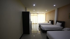 Ein Hotelzimmer mit zwei Einzelbetten, einem Kleiderschrank und einem großen Fenster mit Vorhängen.