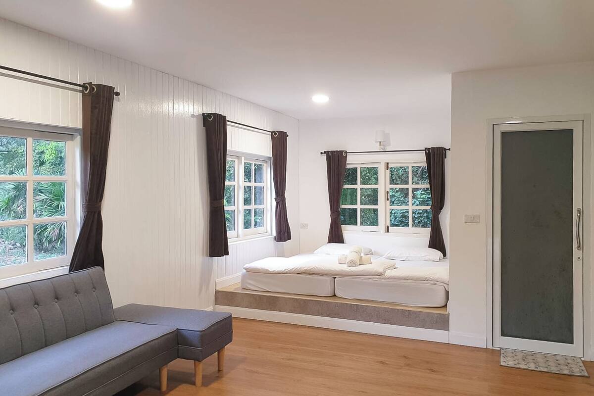 A modern room with a sofa, a bed with a view, and a door.