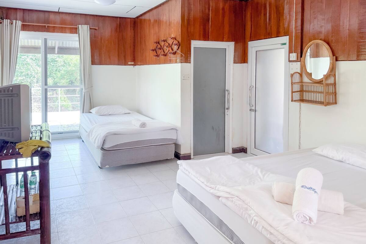A hotel room with two beds, a wooden wall, a large mirror, and a TV.