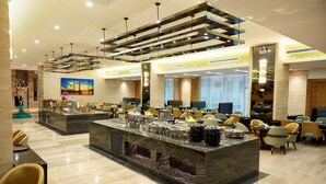 Un hall d’hôtel moderne avec un bar central, des espaces aménagés pour s’asseoir et un grand tableau accroché au mur.