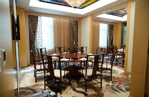 A dining area with a round table, multiple chairs, and a patterned carpet.
