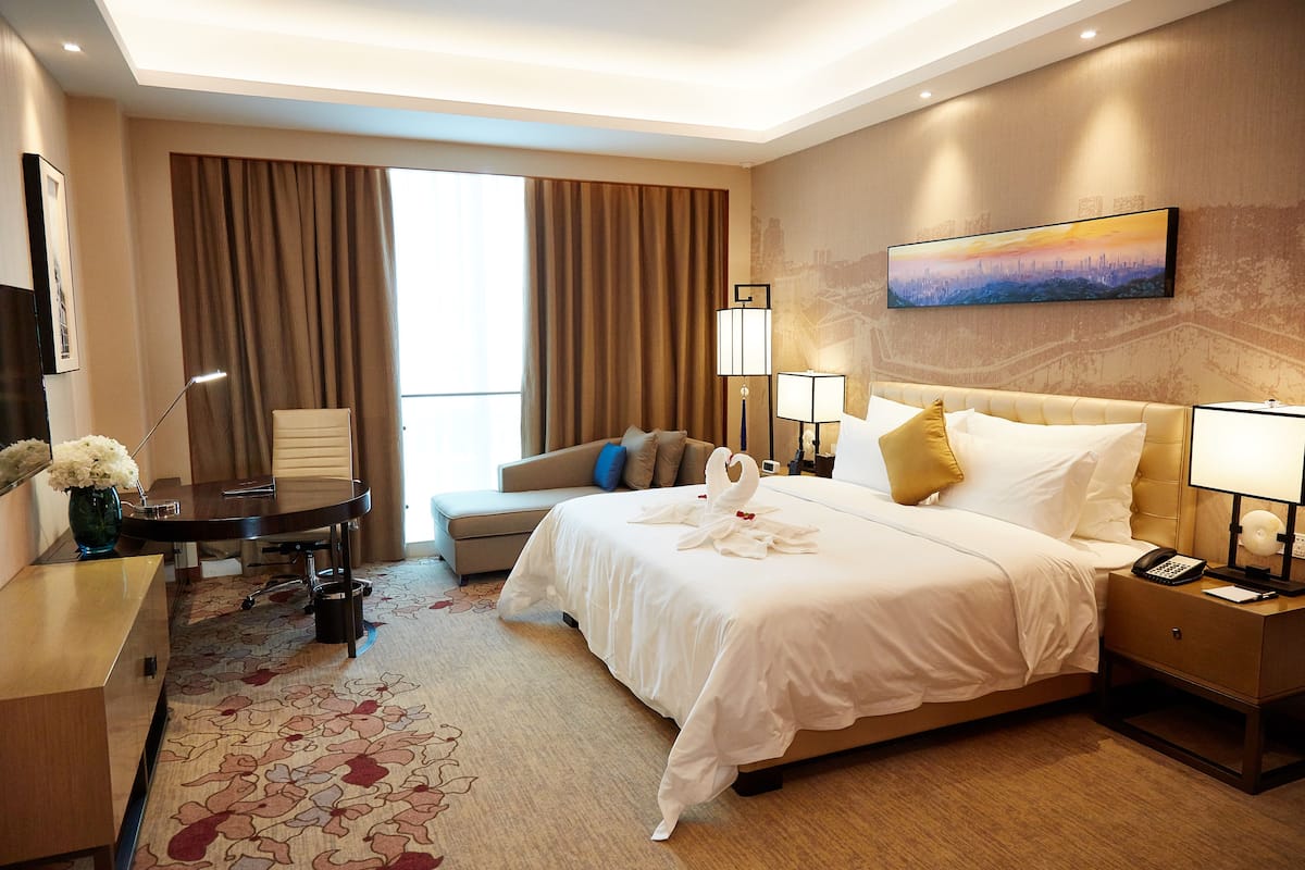 Une chambre d’hôtel avec un grand lit, un bureau, un canapé et un tableau au mur.