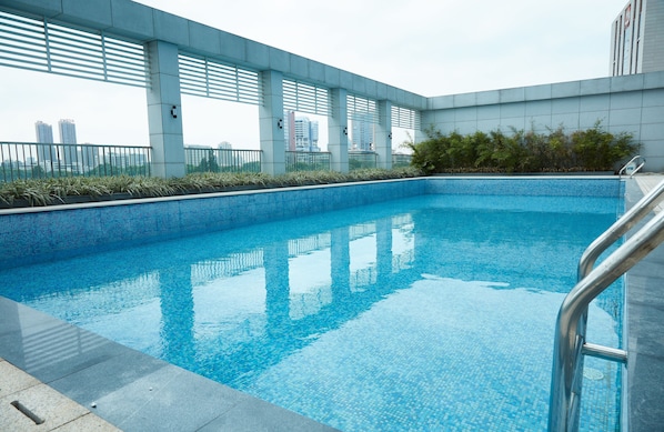 A modern indoor swimming pool with clear blue water, surrounded by a tiled deck and metal railings.