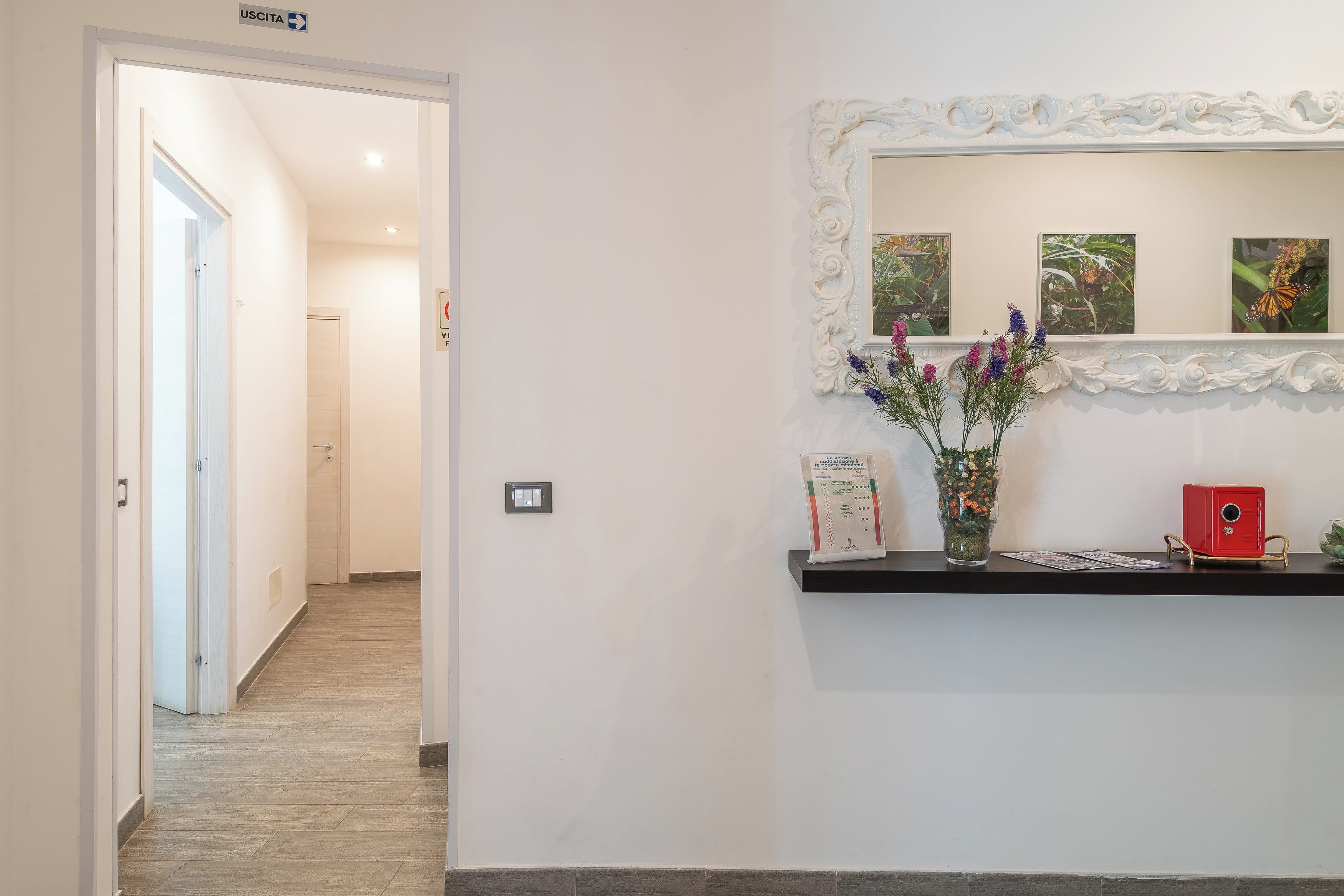 Un pasillo con una mesa de recepción, un espejo y un jarrón con flores.