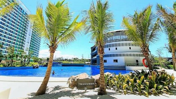 Et resort med pool, palmetræer og en bygning med skiltet "The Azure Beach".