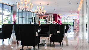 En moderne lobby med polstrede sorte siddepladser, en marmorbelagt gulv og en stor lysekrone.