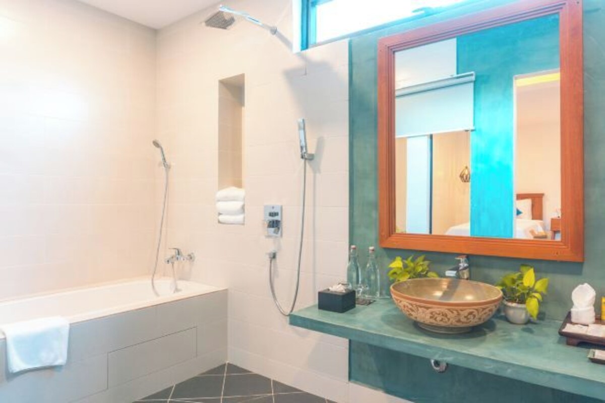 A bathroom with a bathtub, a glass-enclosed shower, a sink with decorative bowl, and a mirror with a wooden frame.