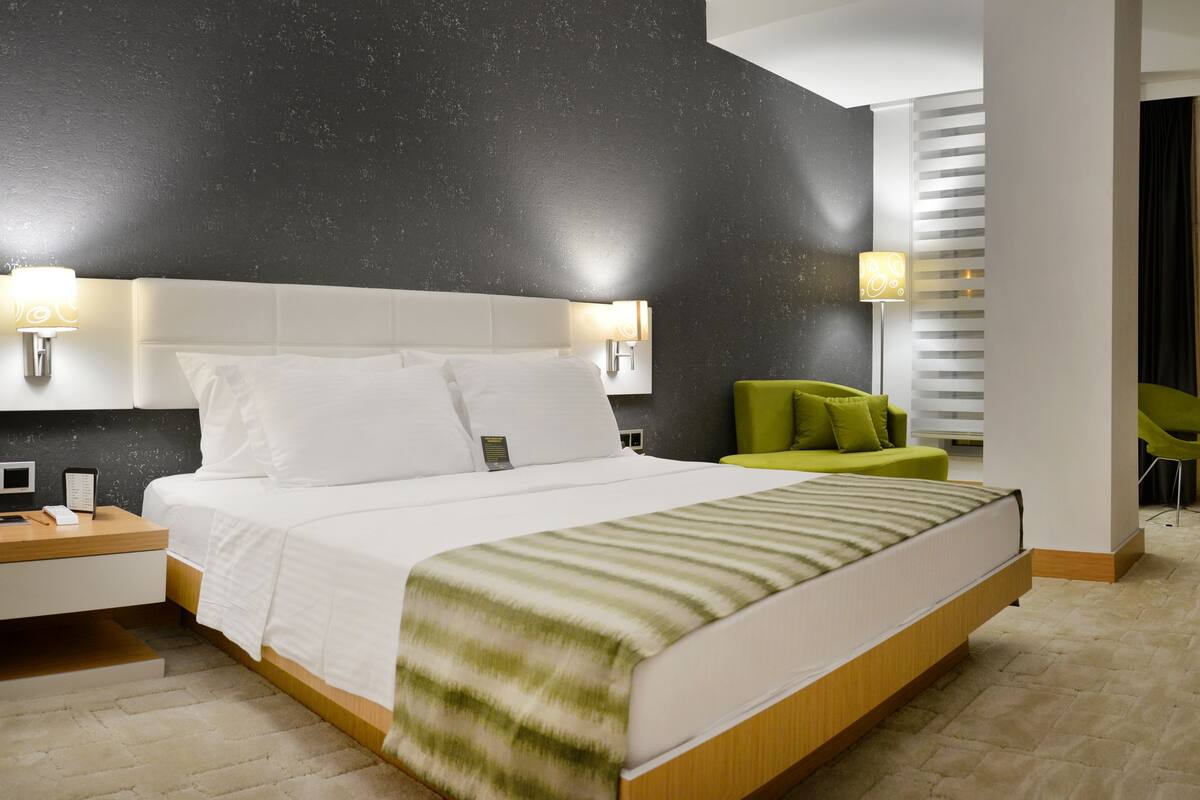Habitació d'hotel moderna amb un llit gran, taules de nit, escriptori i zona d'estar amb seients.
