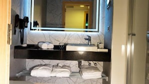Un baño moderno con tocador de mármol, un espejo grande y cabina de ducha de vidrio.