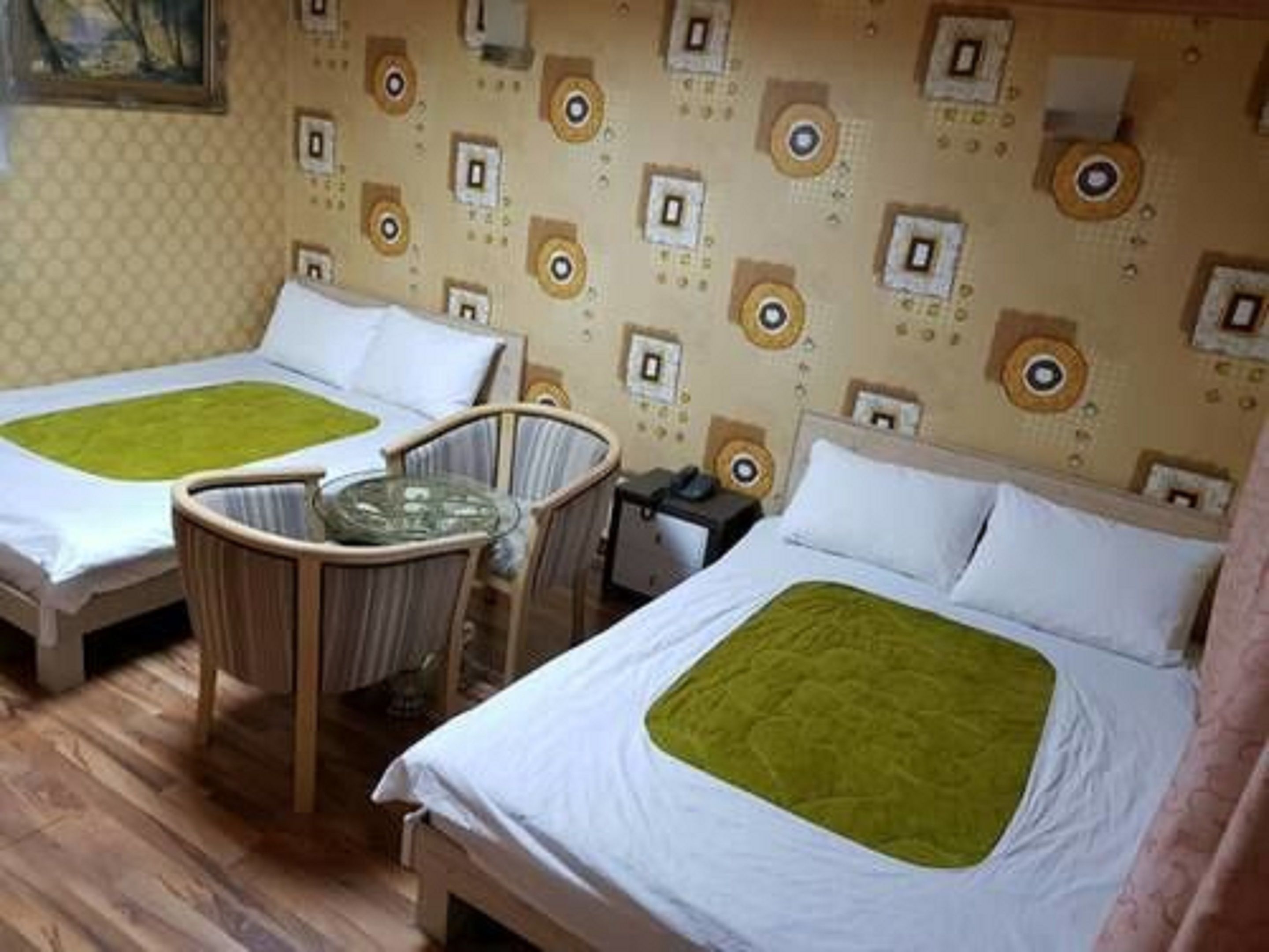 A hotel room with two beds, a chair, and a small table.