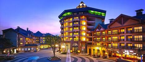 A multi-story hotel with a central tower, a courtyard, and a pool area.