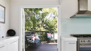 A kitchen with a view to an outdoor deck, a gas stove, and a dining area with chairs and a table.