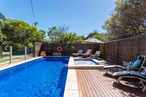 A swimming pool with lounge chairs and a hot tub area.
