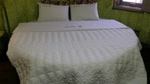 Una habitación de hotel con cama, almohadas y una ventana.