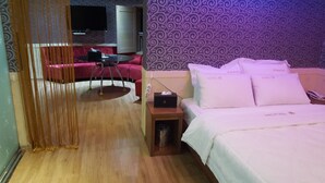 Une chambre d’hôtel avec un lit, une petite table, une chaise, un téléviseur et un mur décoré de motifs.