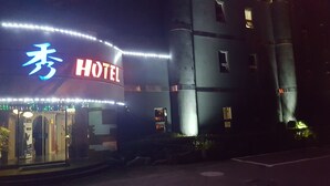 Un hôtel avec une enseigne au néon, une entrée bien visible et un parking.