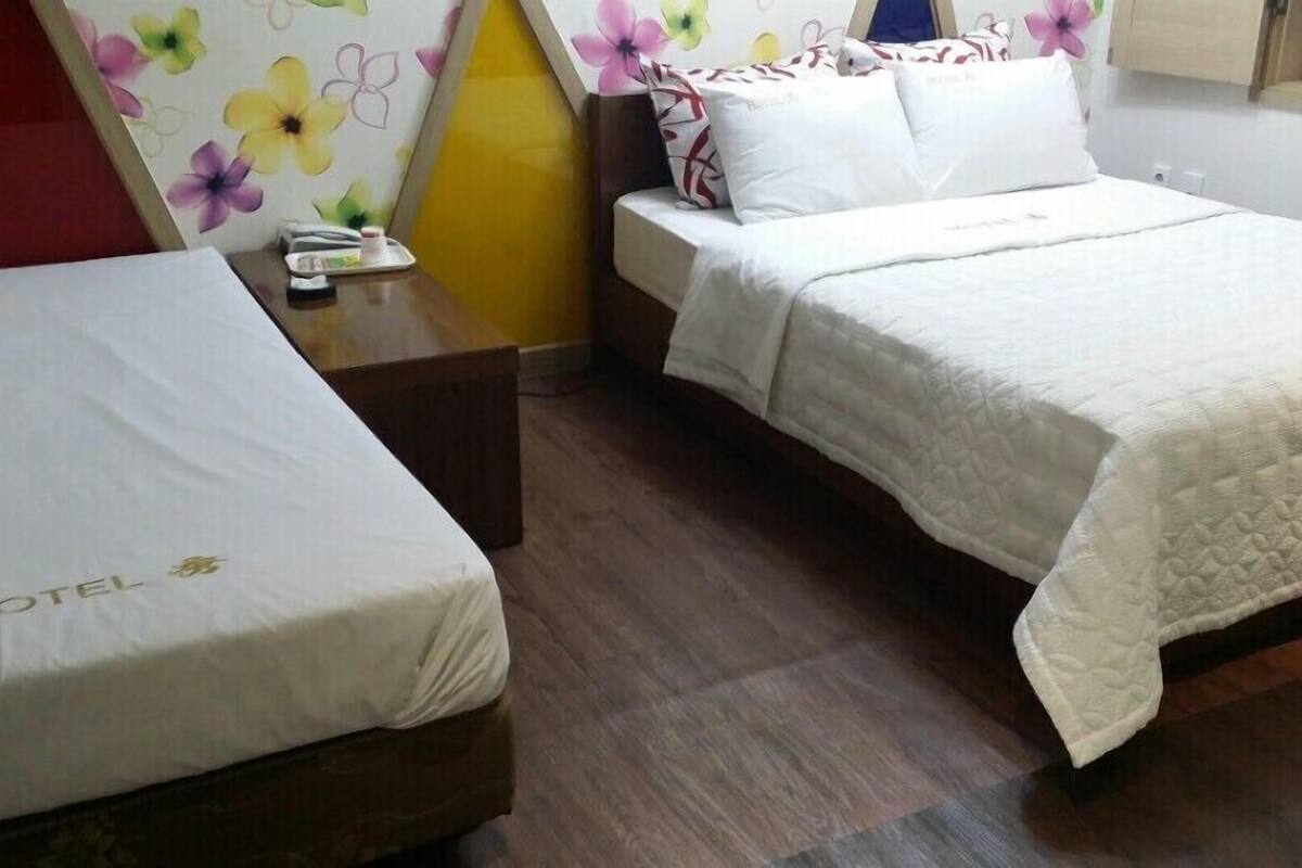 Two single beds with white bedding, a wooden nightstand, and a wall with a floral pattern.