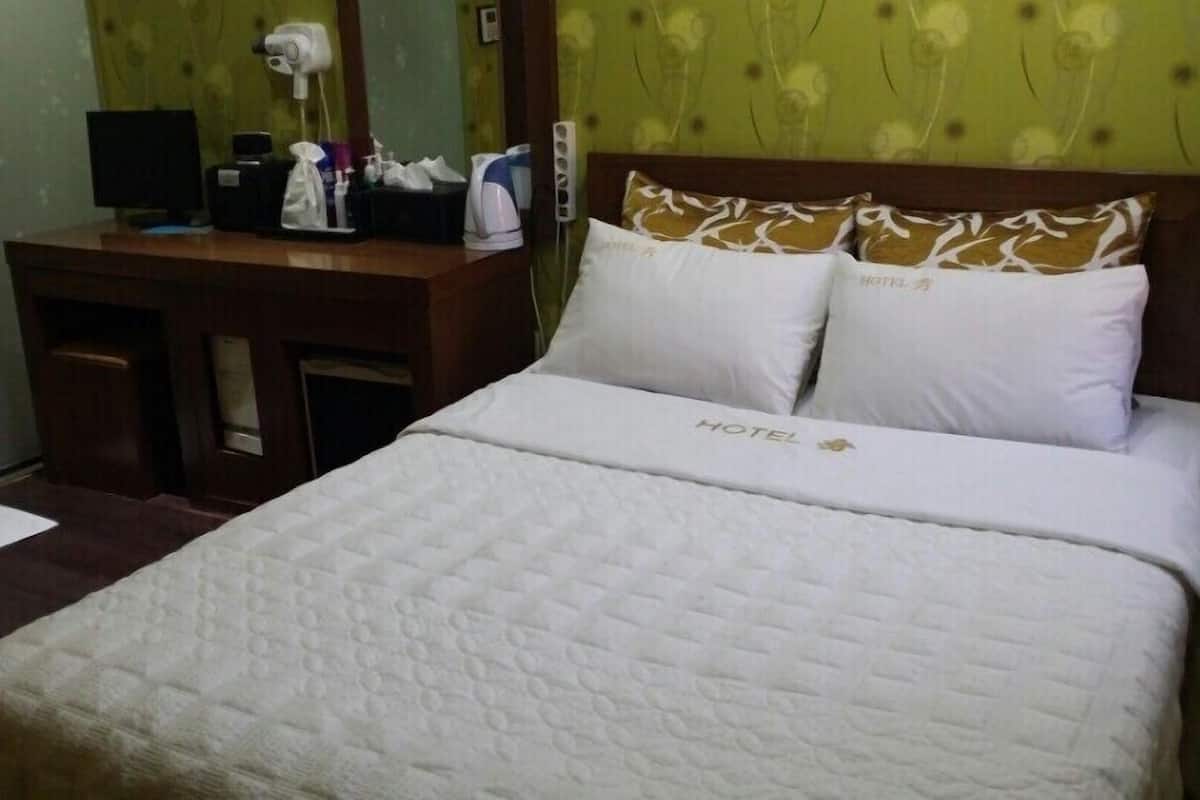 A hotel room with a bed, a desk with a computer, a hairdryer, and toiletries.