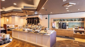 A modern kitchen area with a buffet setup, a coffee machine, and a wine refrigerator. - Alpico Plaza Hotel (Matsumoto)