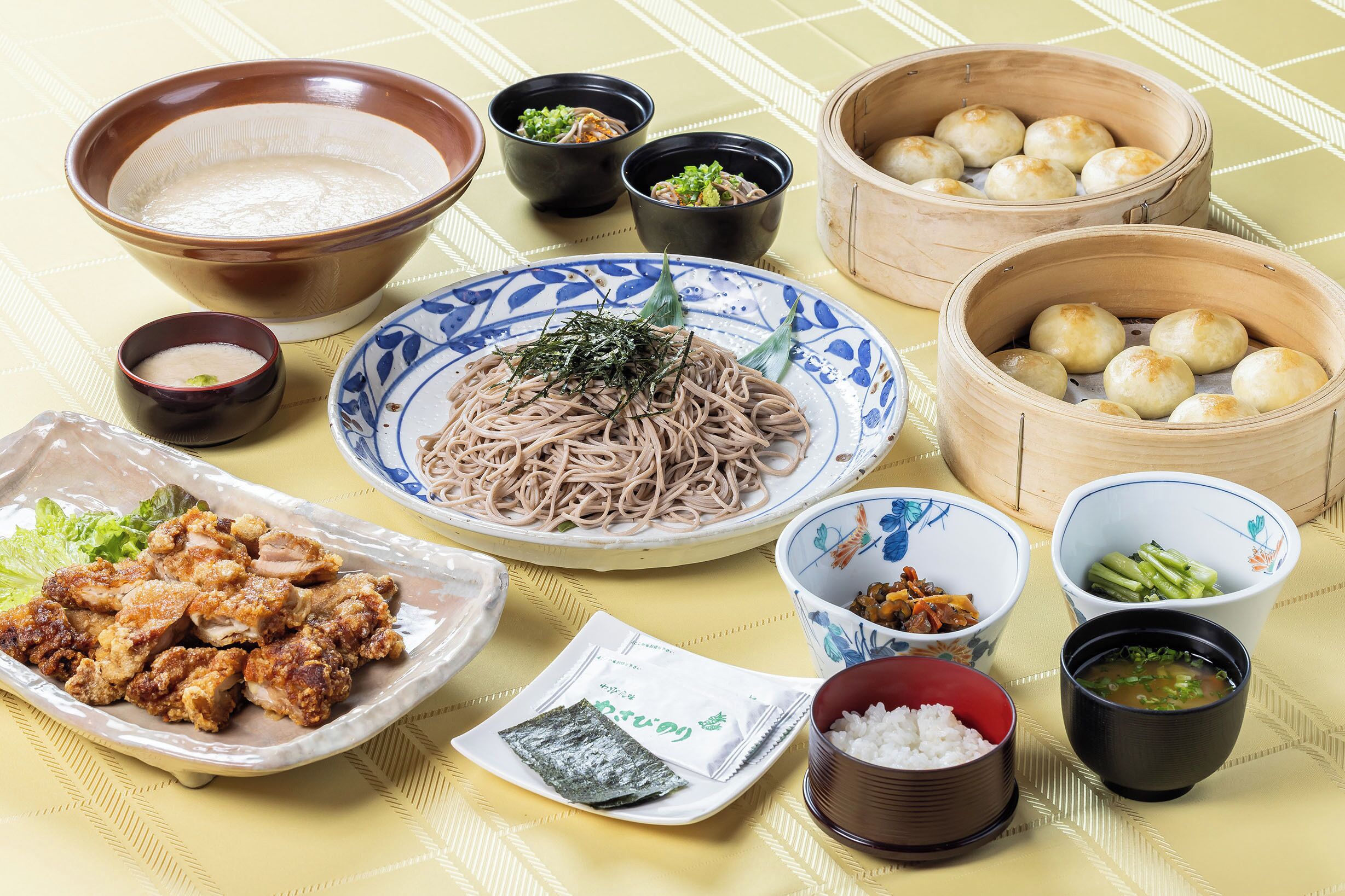 A table with various dishes including noodles, dumplings, and a bowl of soup.