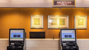 A reception area with two ATMs, framed artwork on the wall, and a sign indicating 'RECEPTION'. - Alpico Plaza Hotel (Matsumoto)