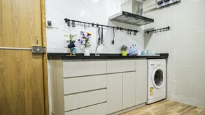A compact kitchen with a built-in washing machine, wooden door, and tiled backsplash. - Smiley Inn (Kowloon)