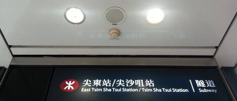 A subway station sign with East Tsim Sha Tsui Station and a subway symbol.