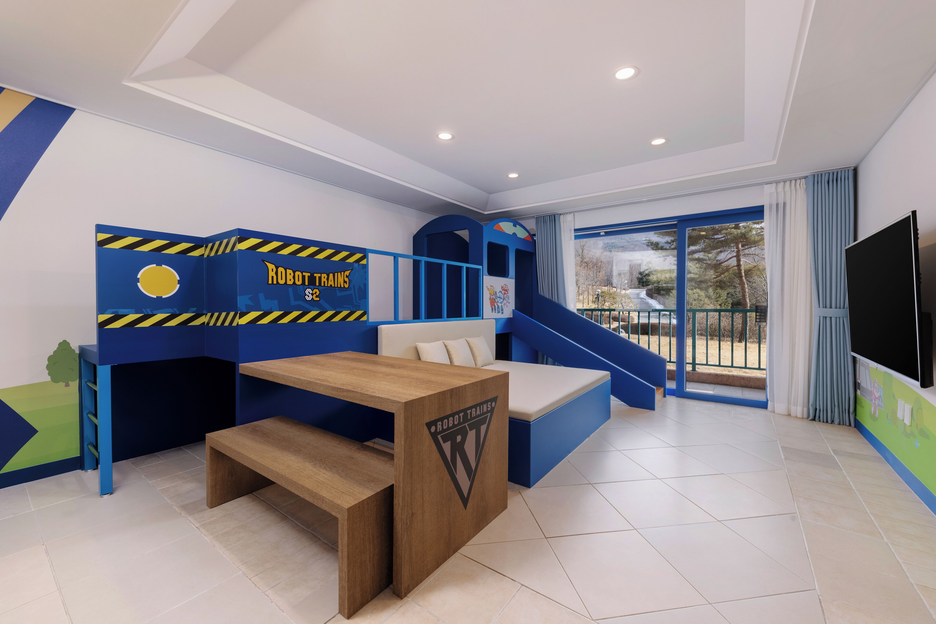 A children's playroom with a blue and yellow train theme, including a bunk bed, a bench, and a play area.
