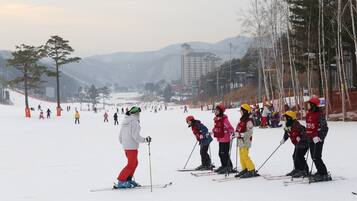 A ski slope with skiers and a mountainous backdrop.
