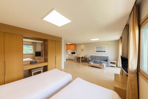 Una habitación de hotel moderna con dos camas, una kitchenette, un comedor y un televisor.