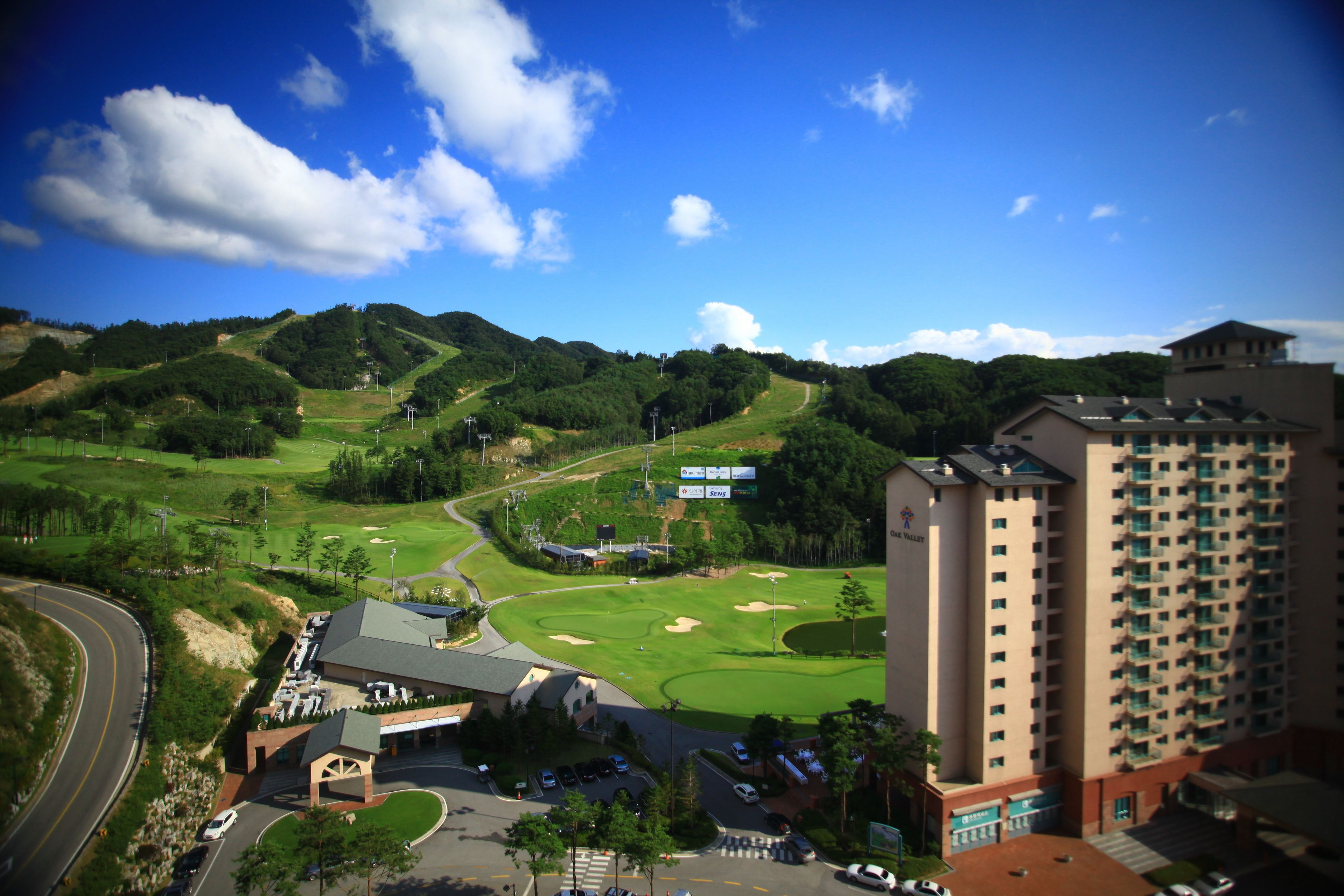 A golf course with a hotel in the foreground and a tall building in the background.