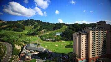 A golf course with a hotel in the foreground and a tall building in the background.
