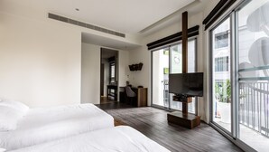 Habitación de hotel moderna con dos camas grandes, un escritorio con una silla, televisión y ventanas amplias que ofrecen vistas al exterior.