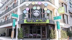 Un hotel con un cartel llamativo que dice "T.H.D HOTEL" y un logotipo sobre la entrada.