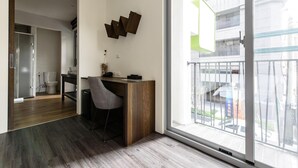 Un interior moderno con un escritorio y una silla de madera, un ventanal con vistas a la ciudad y una puerta que da a otra habitación.