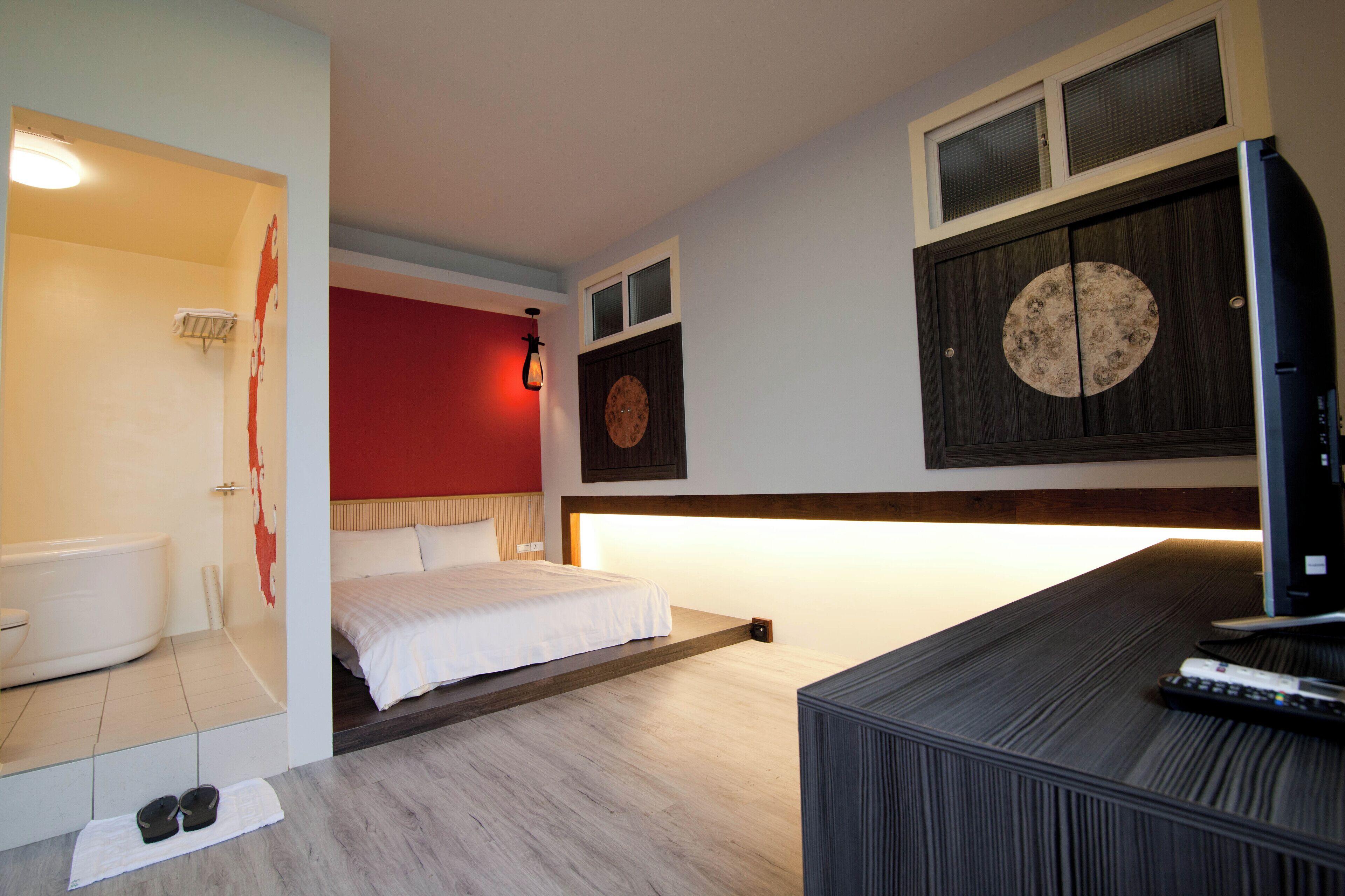 A modern hotel room with a bed, a television, and a bathroom.