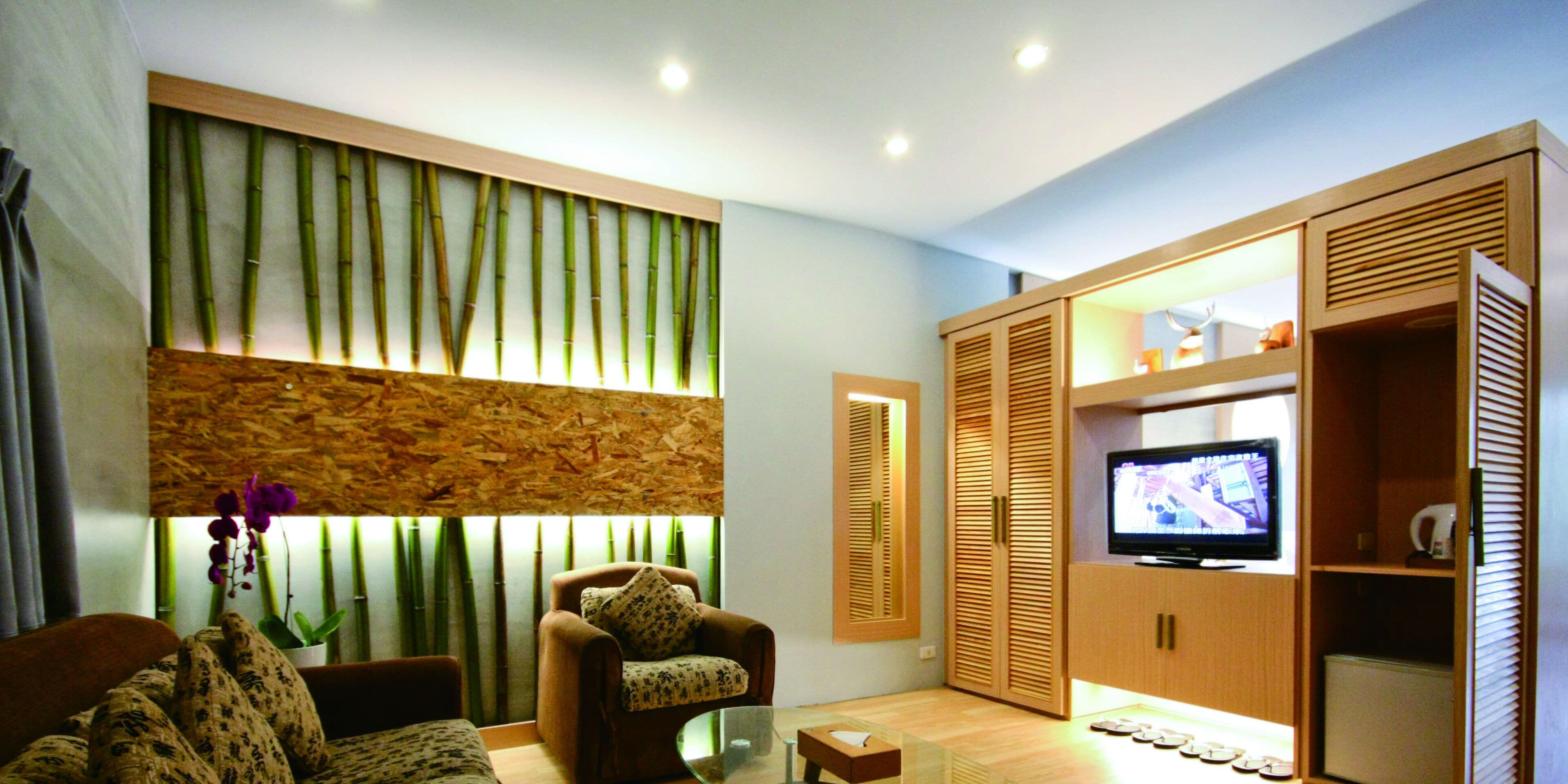 A modern living room with a sofa, armchair, and a television on a wooden cabinet.