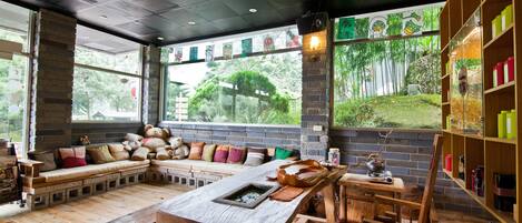 A cozy interior with a wooden bench seating area, a rustic wooden table, and a bookshelf with colorful containers.