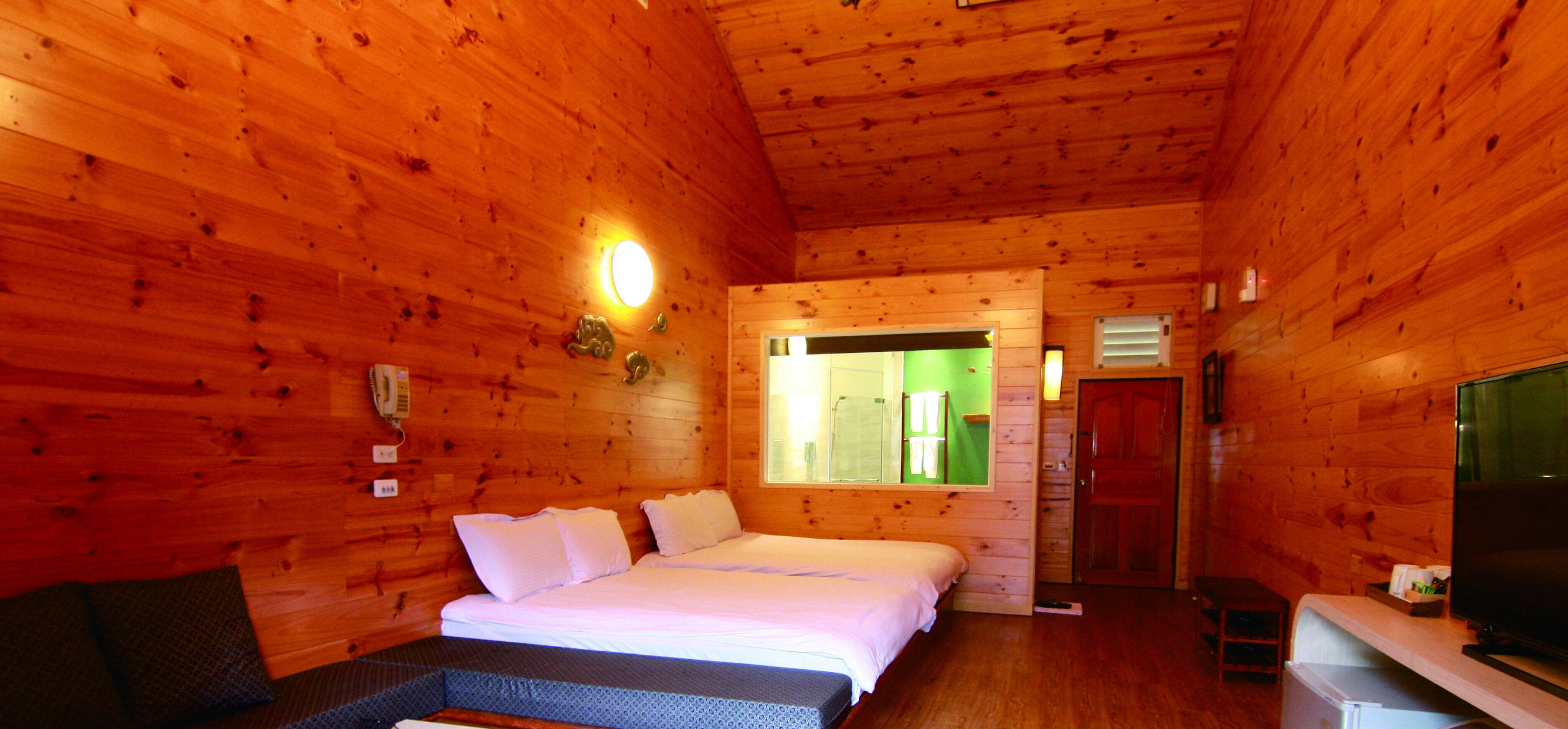 Une chambre dans un chalet en bois, avec un lit, une télévision et une petite table.