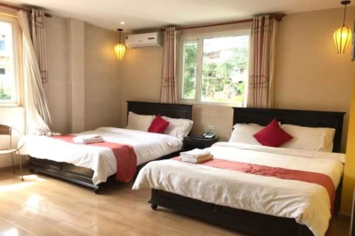 Habitación de hotel con dos camas, una mesita de noche y una ventana con cortinas.