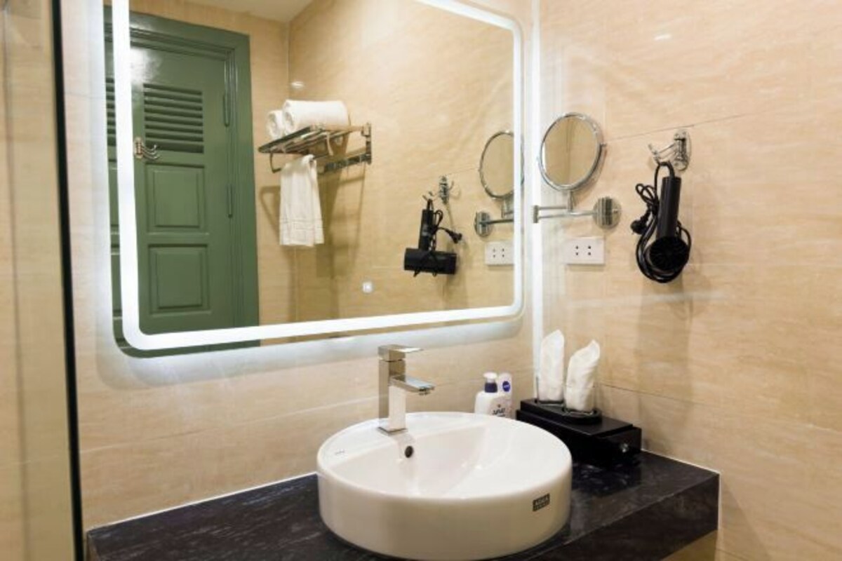 Un baño con un espejo grande, un lavabo, toallero y secador de pelo.