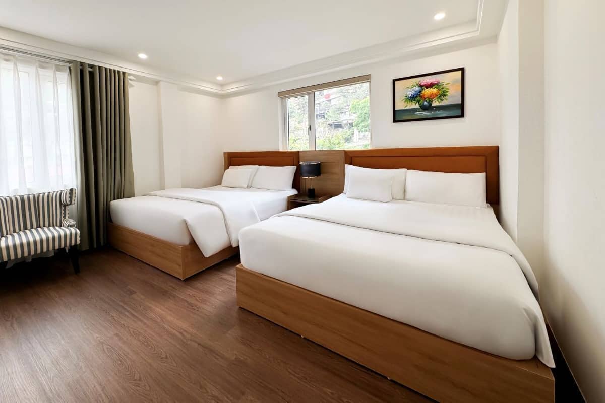 Una habitación de hotel con dos camas, un sofá, una ventana con cortinas y un cuadro en la pared.