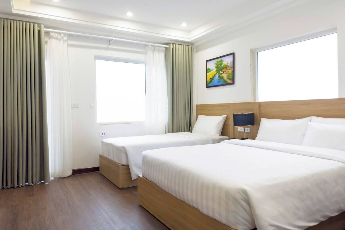 Habitación de hotel con dos camas, un cuadro en la pared y una ventana con cortinas.