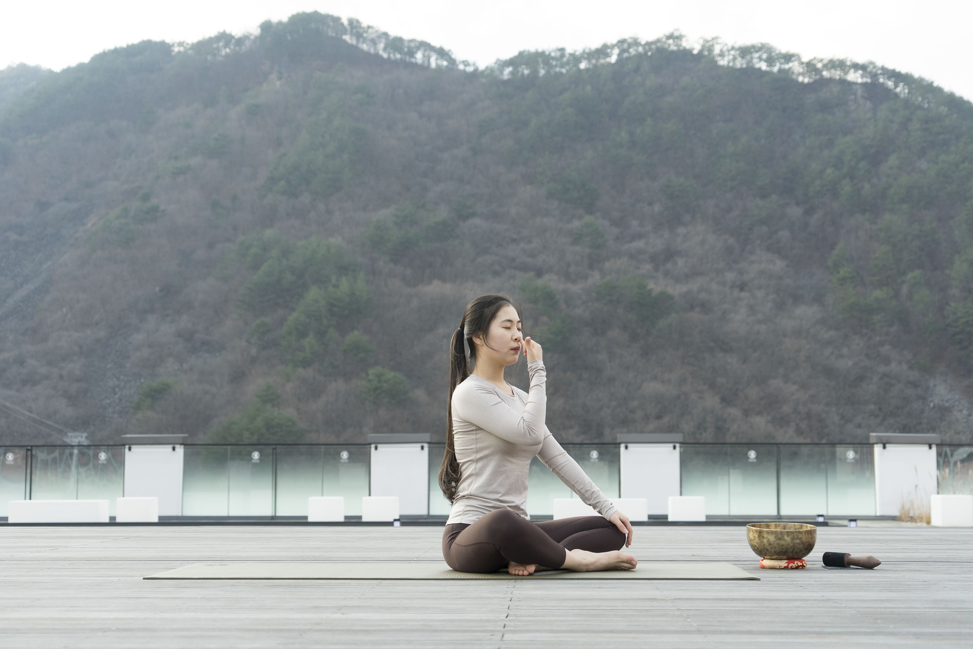 A person sitting on a rooftop with a view of a forested hill.