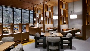 A modern interior with wooden furniture, seating areas, and pendant lighting.